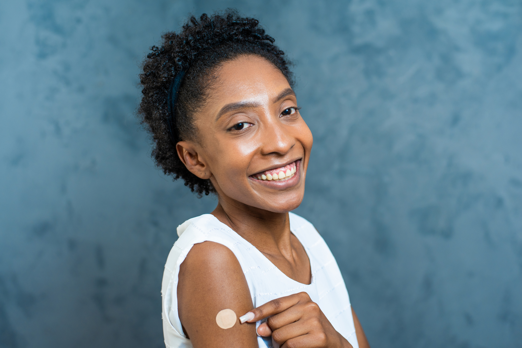 Mulher negra mostra a marca da vacina para controle dos sintomas de dengue