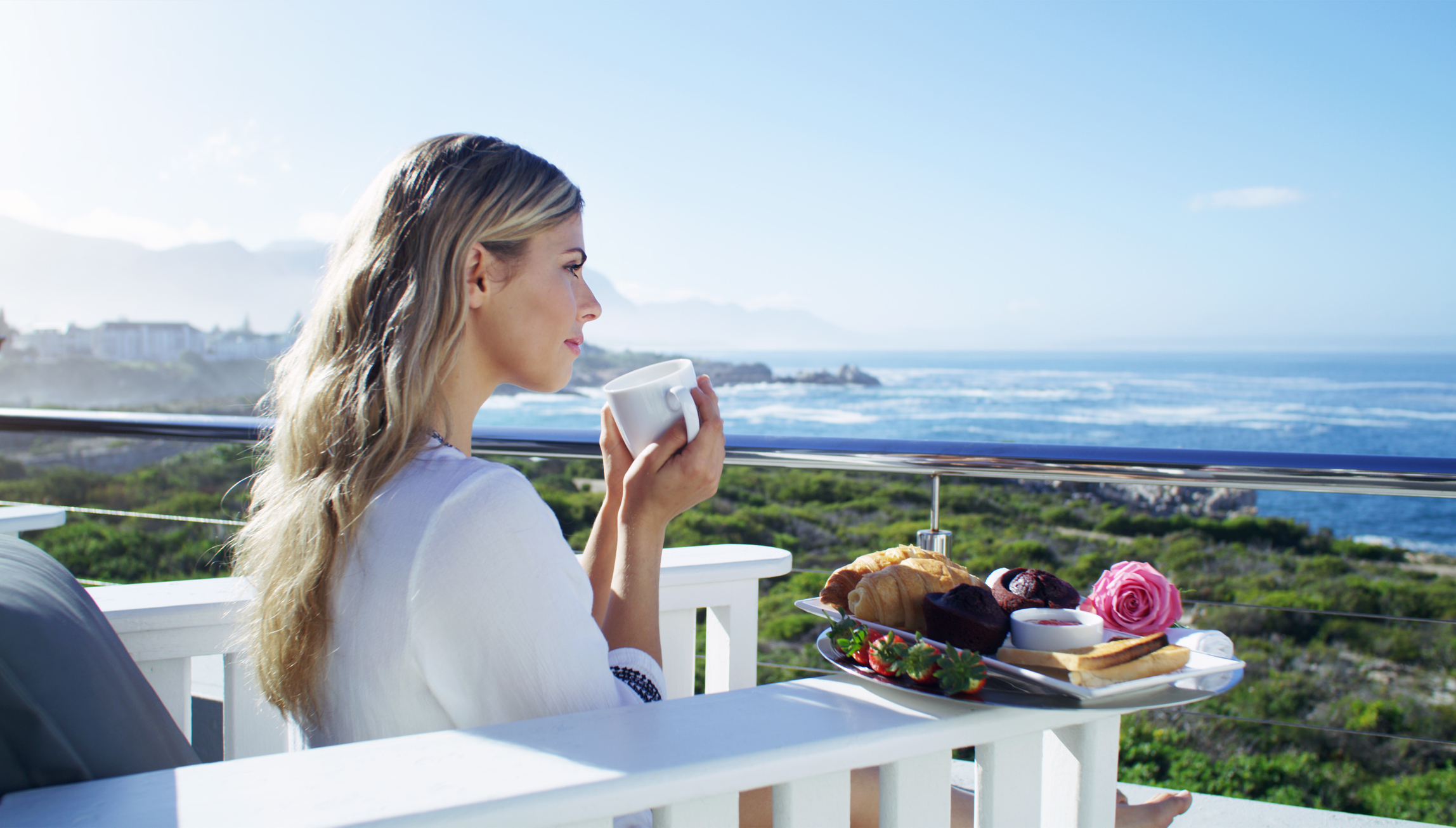 Mulher ingere seu café da manhã olhando o mar. Uma dieta equilibrada auxilia na prevenção de uma intoxicação alimentar